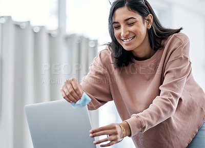 Buy stock photo Shot of a young woman disinfecting her laptop while working from home