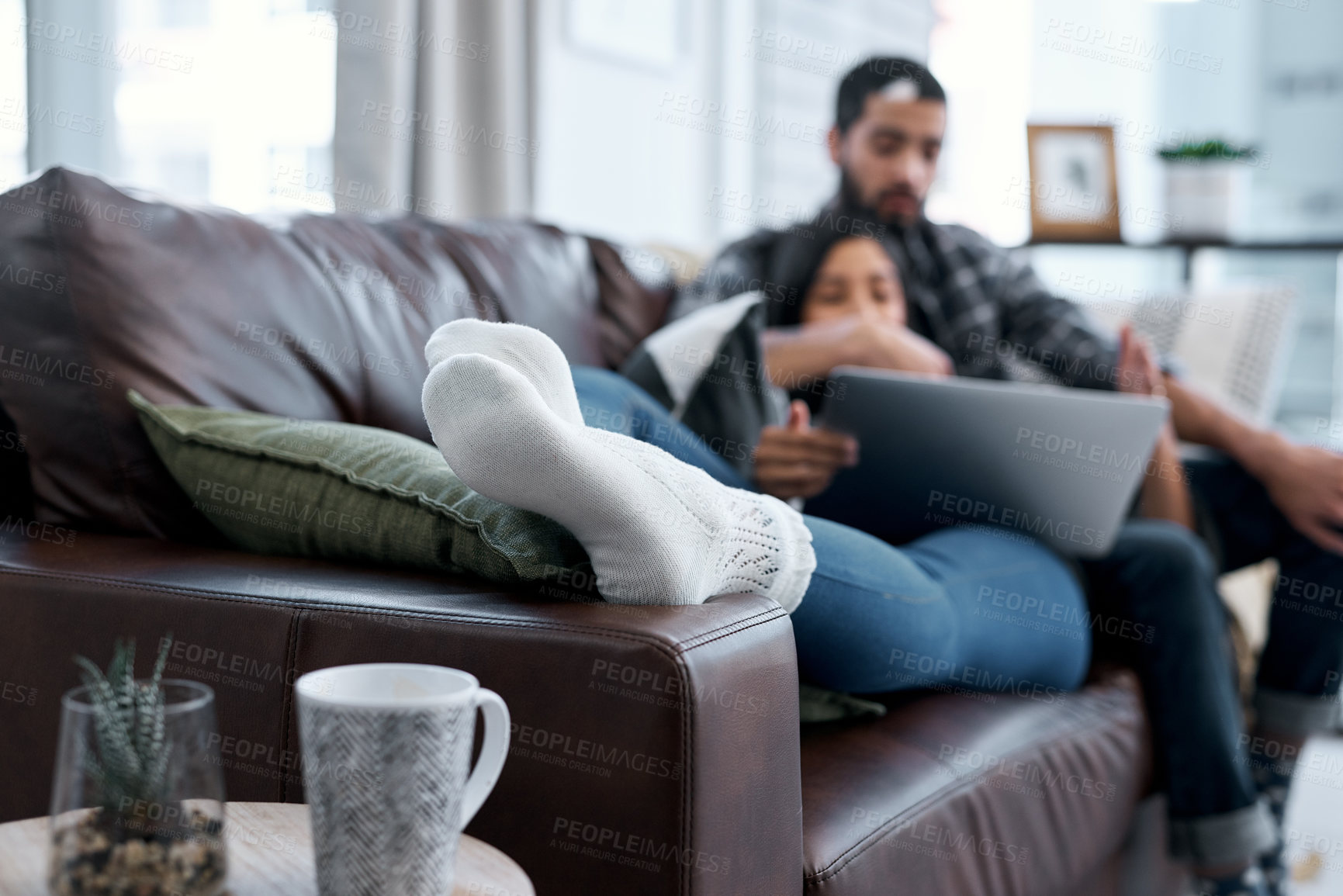 Buy stock photo Shot of a young couple using a laptop while relaxing on the sofa at home