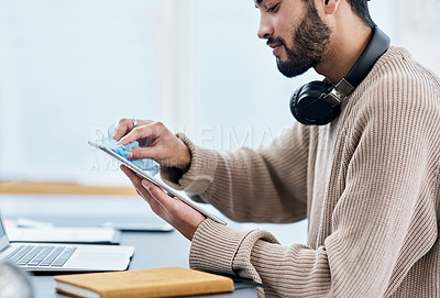 Buy stock photo Shot of a young man disinfecting his digital tablet while working from home