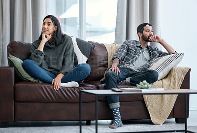 Buy stock photo Shot of a young couple sitting on the sofa and ignoring each other