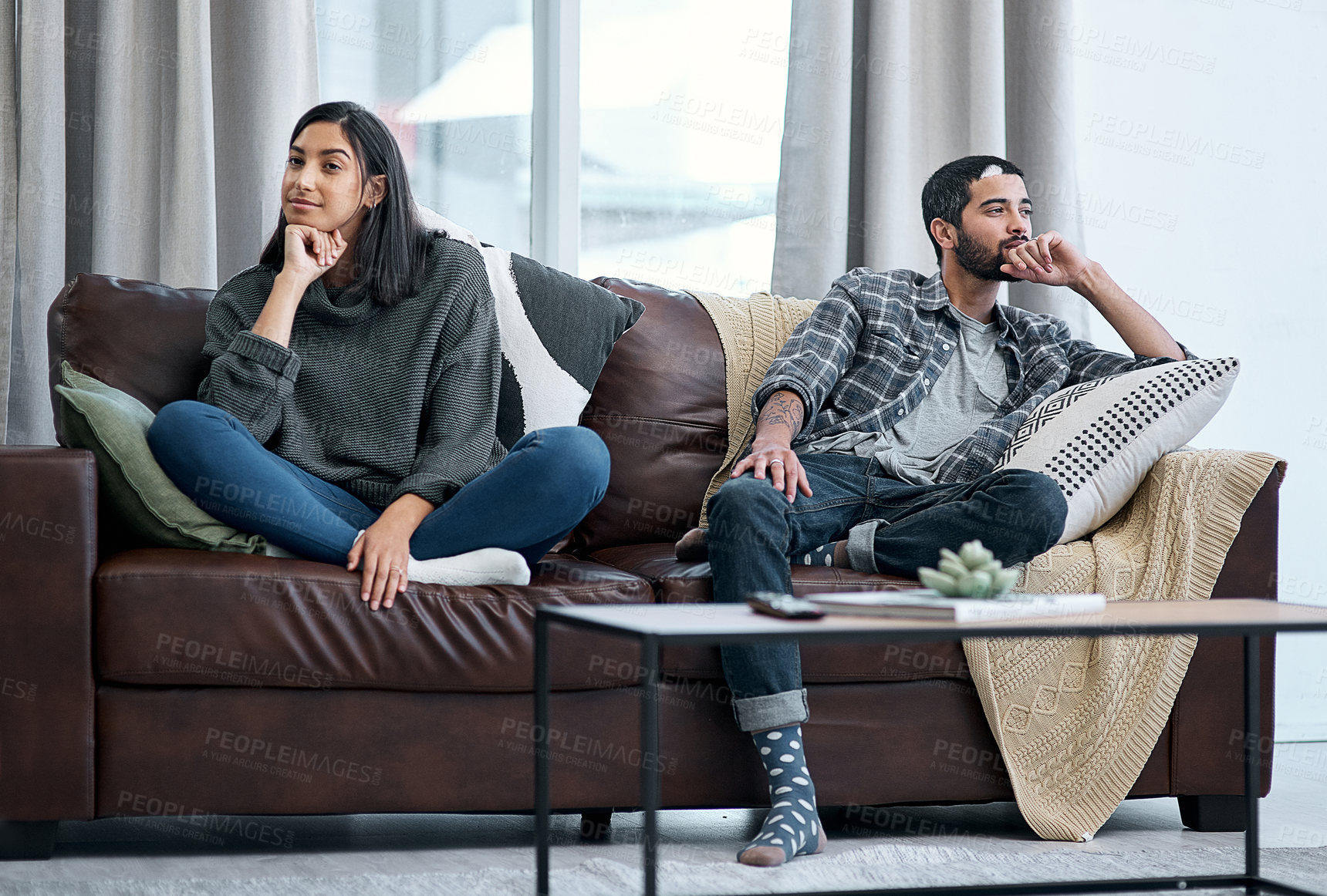 Buy stock photo Shot of a young couple sitting on the sofa and ignoring each other