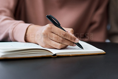 Buy stock photo Shot of an unrecognisable woman writing in a notebook while working from home
