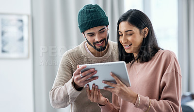 Buy stock photo Shot of a young man and woman using a digital tablet while working from home