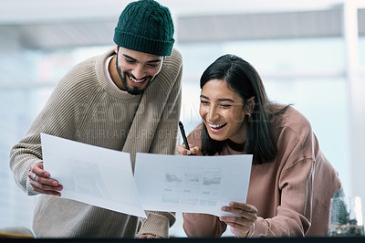 Buy stock photo Shot of a young man and woman going though paperwork while working from home