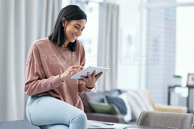 Buy stock photo Shot of a confident young woman using a digital tablet while working from home