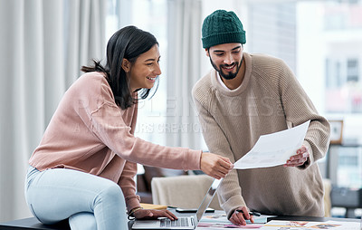 Buy stock photo Shot of a young man and woman using a laptop and going though paperwork while working from home