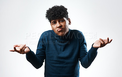 Buy stock photo Studio shot of a young man shrugging his shoulders against a grey background