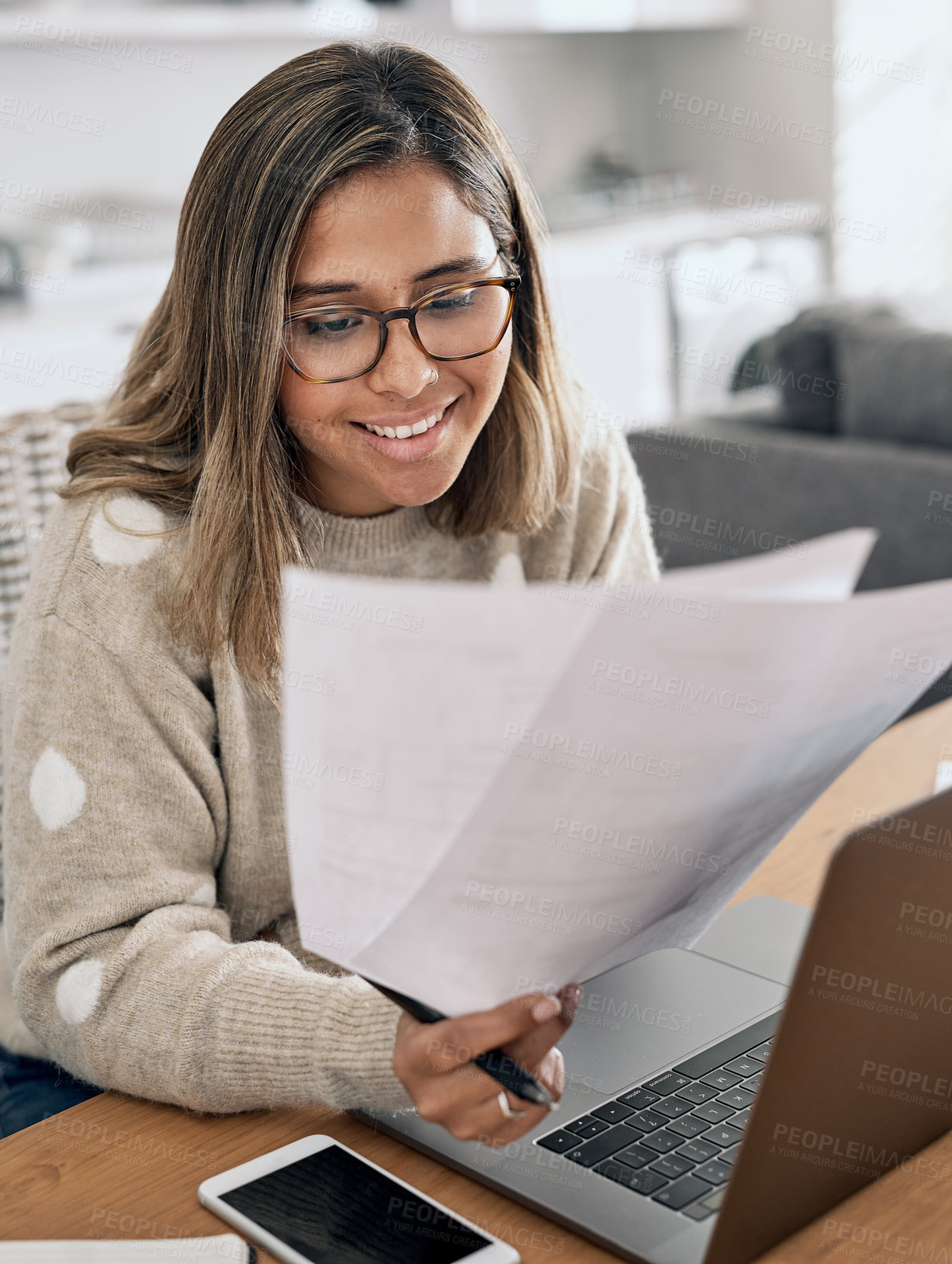 Buy stock photo Shot of a woman looking at paperwork while working from home