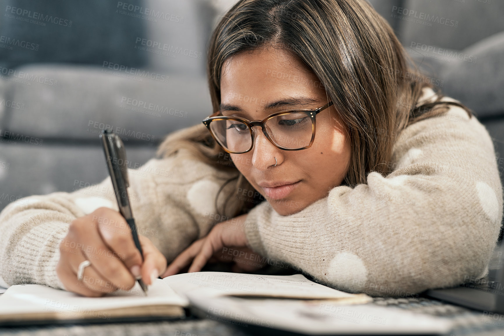 Buy stock photo Cropped shot of a young woman wearing glasses while busy writing at home