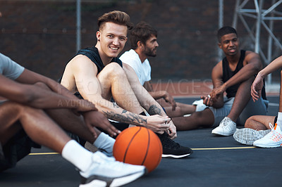 Buy stock photo Shot of a sporty young man hanging out with his friends on a basketball court