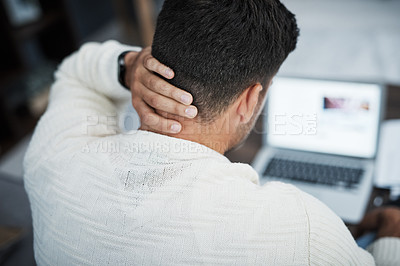 Buy stock photo Rearview shot of a young man experiencing neck pain while working from home