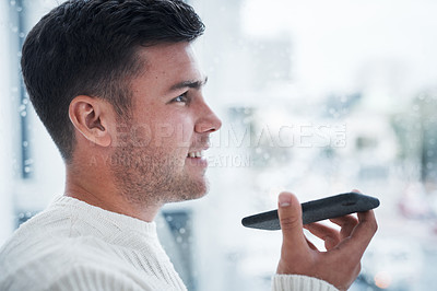 Buy stock photo Shot of a young man using a smartphone while working from home