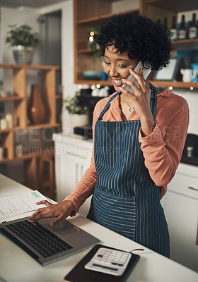 Buy stock photo Shot of a woman using her laptop while talking on her cellphone in her cafe