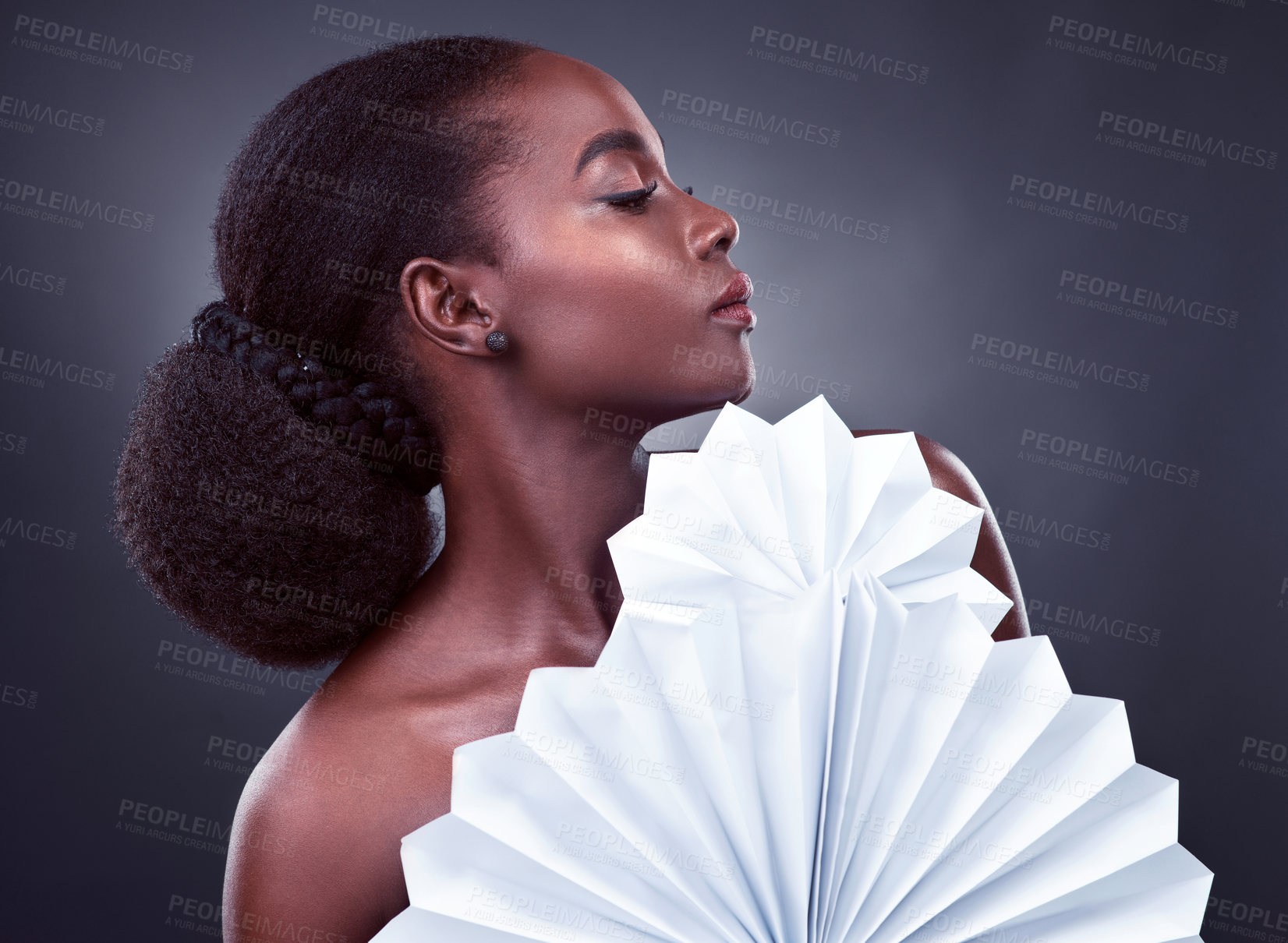 Buy stock photo Studio shot of a beautiful young woman posing with origami fans against a black background