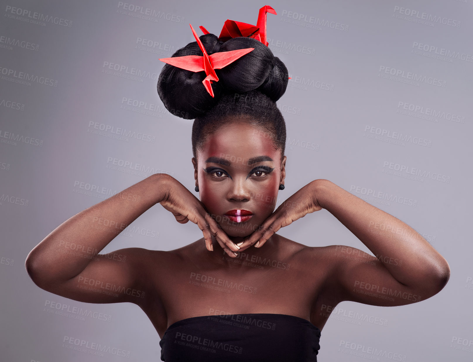 Buy stock photo Studio portrait of a beautiful young woman wearing Asian inspired makeup and posing with origami against a grey background