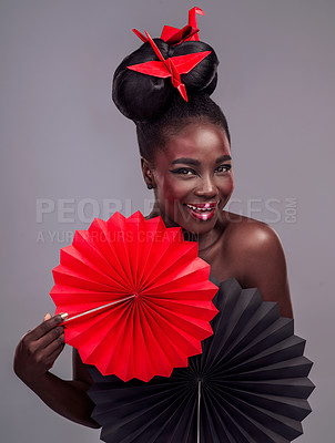 Buy stock photo Studio portrait of a beautiful young woman wearing Asian inspired makeup and posing with origami against a grey background
