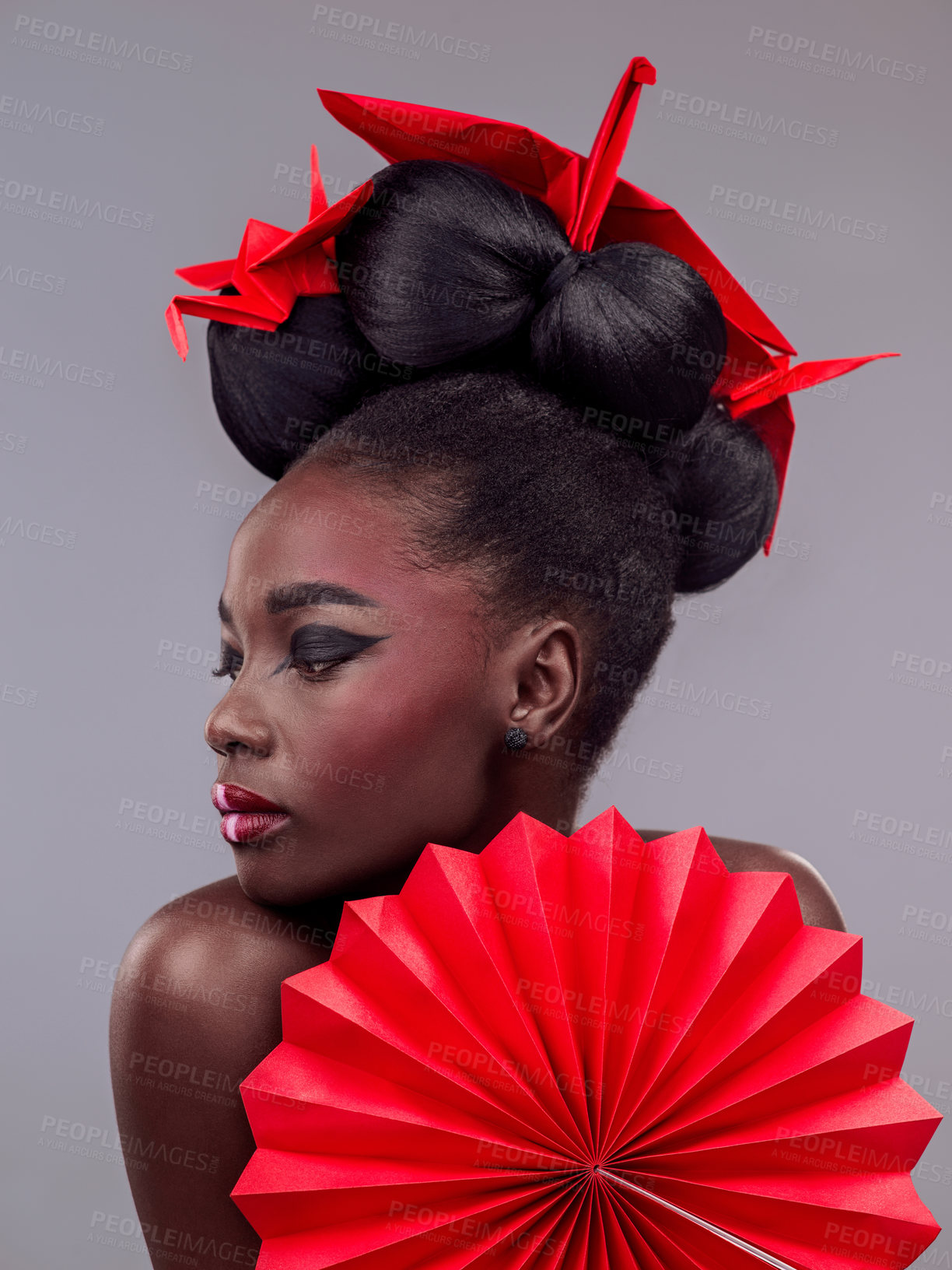 Buy stock photo Studio shot of a beautiful young woman wearing Asian inspired makeup and posing with origami against a grey background