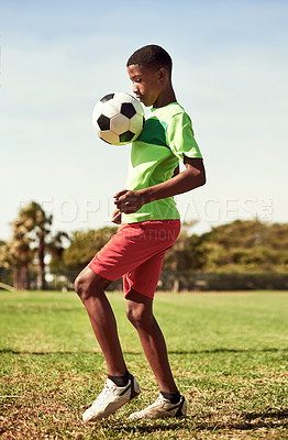 Buy stock photo Shot of a young boy playing soccer on a sports field