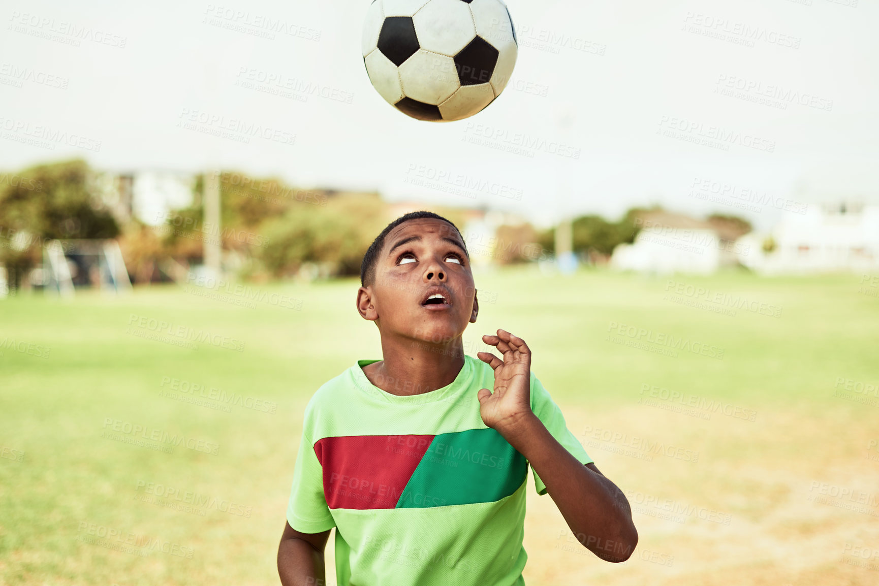 Buy stock photo Shot of a young boy playing soccer on a sports field