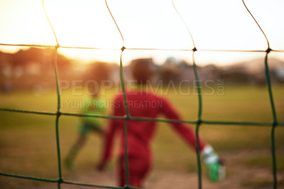 Buy stock photo Defocused shot of young boys playing soccer on a sports field