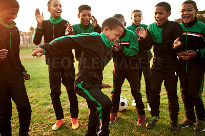 Buy stock photo Shot of a boys soccer team cheering their teammate on a sports field