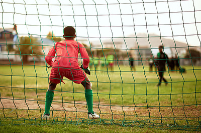 Buy stock photo Rearview shot of a young boy standing as the goalkeeper while playing soccer on a sports field