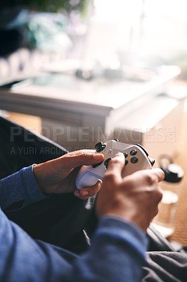 Buy stock photo Cropped shot of an unrecognisable woman playing video games on the sofa at home