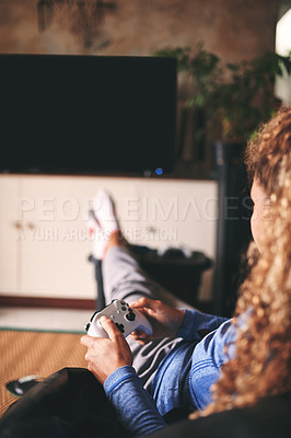 Buy stock photo Cropped shot of an unrecognisable woman playing video games on the sofa at home