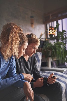 Buy stock photo Shot of a young couple using a smartphone on the sofa at home
