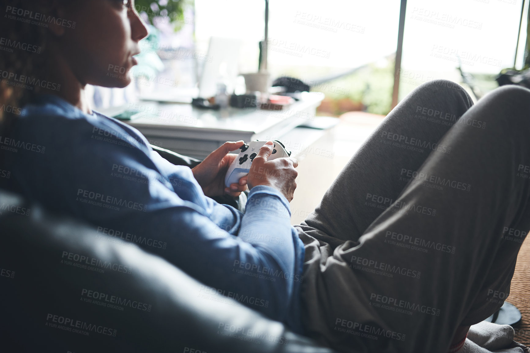 Buy stock photo Cropped shot of a young woman playing video games on the sofa at home