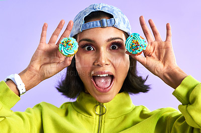 Buy stock photo Studio shot of a young woman holding cupcakes over her face against a purple background