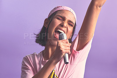 Buy stock photo Studio shot of a beautiful young woman singing with a microphone against a purple background