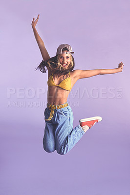 Buy stock photo Studio shot of a beautiful young woman jumping for joy against a purple background