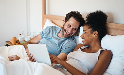 Buy stock photo Laughing married couple with a tablet in bed watching funny comedy film or movie together on the weekend indoors at home. Loving, smiling and romantic husband and wife looking at meme on social media