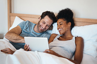Buy stock photo Happy couple, tablet and laughing in bed for funny entertainment, joke or morning in relax together at home. Interracial man and woman person with laugh on technology for social media meme in bedroom