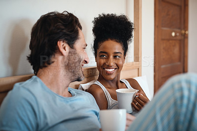 Buy stock photo Happy interracial couple, bed and coffee in relax for morning, bonding or breakfast at home. Man and woman smiling for tea, conversation or talk on relaxing weekend or holiday together in the bedroom
