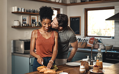Buy stock photo Happy biracial couple bonding, cooking together in a kitchen at home. Smiling, carefree and in love husband kissing and being affectionate with his wife, enjoying time together and a romantic gesture