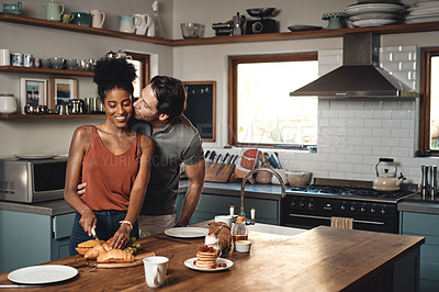 Buy stock photo Interracial couple, kiss and cooking breakfast in kitchen for morning, love or care in marriage at home. Happy man kissing woman for food, nutrition or hug in happiness for healthy relationship