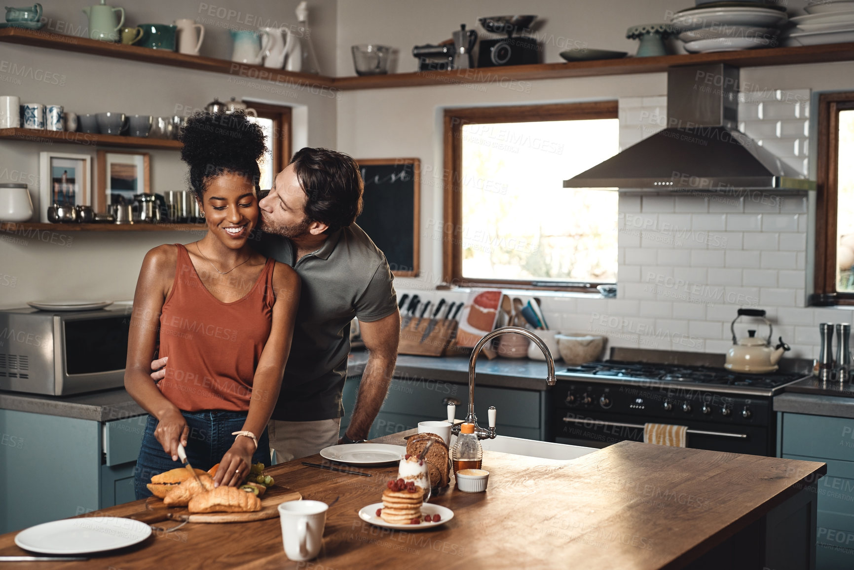Buy stock photo Interracial couple, kiss and cooking breakfast in kitchen for morning, love or care in marriage at home. Happy man kissing woman for food, nutrition or hug in happiness for healthy relationship