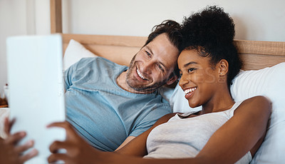 Buy stock photo Happy, relax and carefree interracial couple on digital tablet smiling and taking a selfie in bed. Husband and wife waking up and reading social media news on touchscreen while relaxing at home.