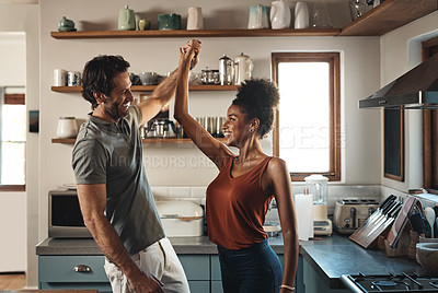 Buy stock photo Happy, in love and dancing while an interracial couple have fun and enjoying time together in home kitchen. Husband and wife sharing a dance while being active and affectionate in loving relationship