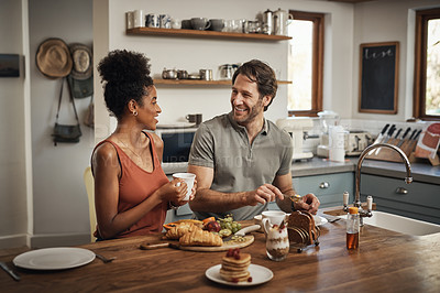 Buy stock photo Happy interracial couple, breakfast and morning in kitchen for healthy meal, talk or bonding at home. Man and woman smiling for coffee, conversation or tea and food on weekend together by the table
