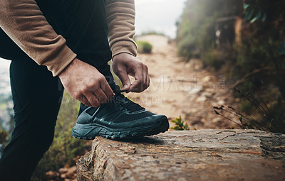 Buy stock photo Closeup shot of an unrecognisable man tying his laces while out on a hike