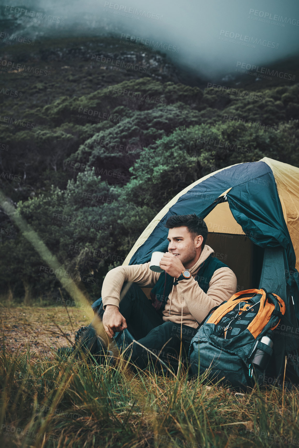 Buy stock photo Shot of a young man drinking coffee while camping in the wilderness