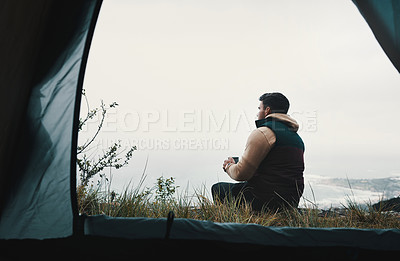 Buy stock photo Rearview shot of a young man drinking coffee while camping in the wilderness