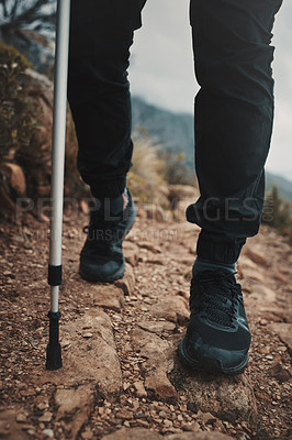 Buy stock photo Closeup shot of an unrecognisable man using a walking pole while hiking through the mountains