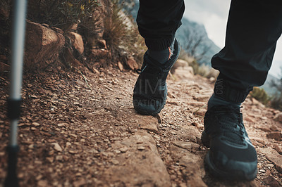 Buy stock photo Closeup shot of an unrecognisable man using a walking pole while hiking through the mountains