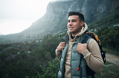 Buy stock photo Shot of a young man hiking through the mountains