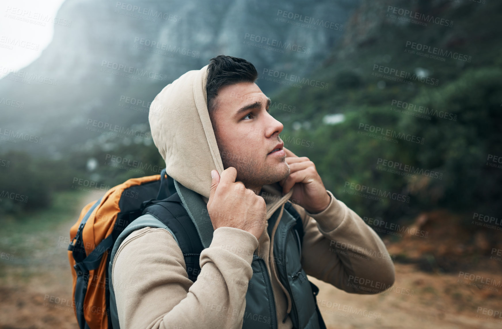 Buy stock photo Shot of a young man hiking through the mountains