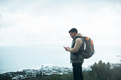 Buy stock photo Shot of a young man using a cellphone while out on a hike